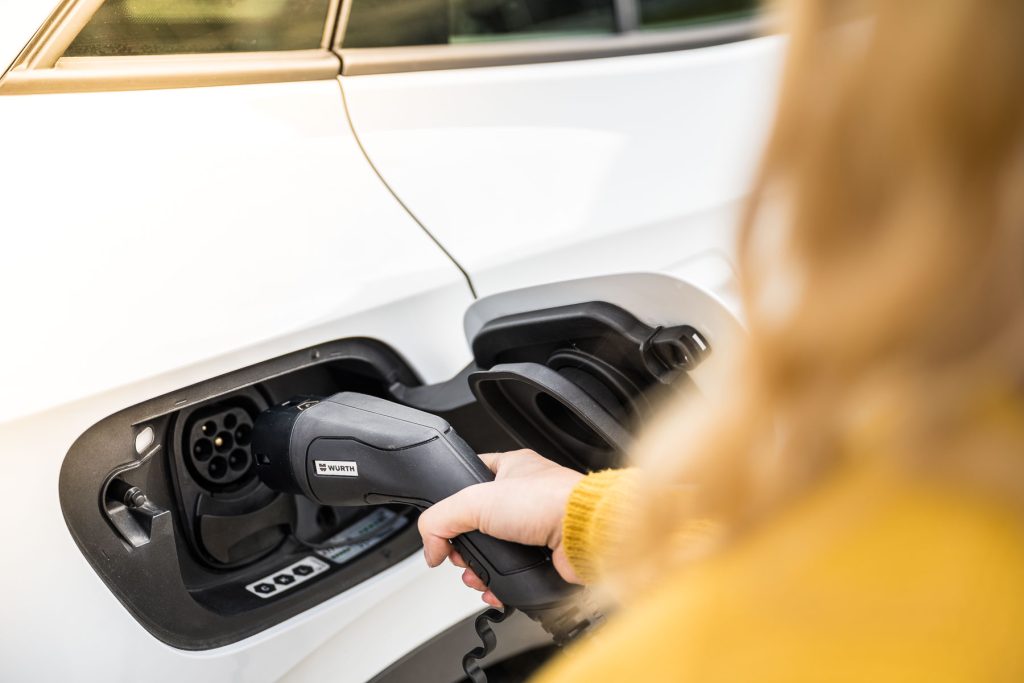 Frau, die ein E-Auto mit einem Würth Stecker aufladet.